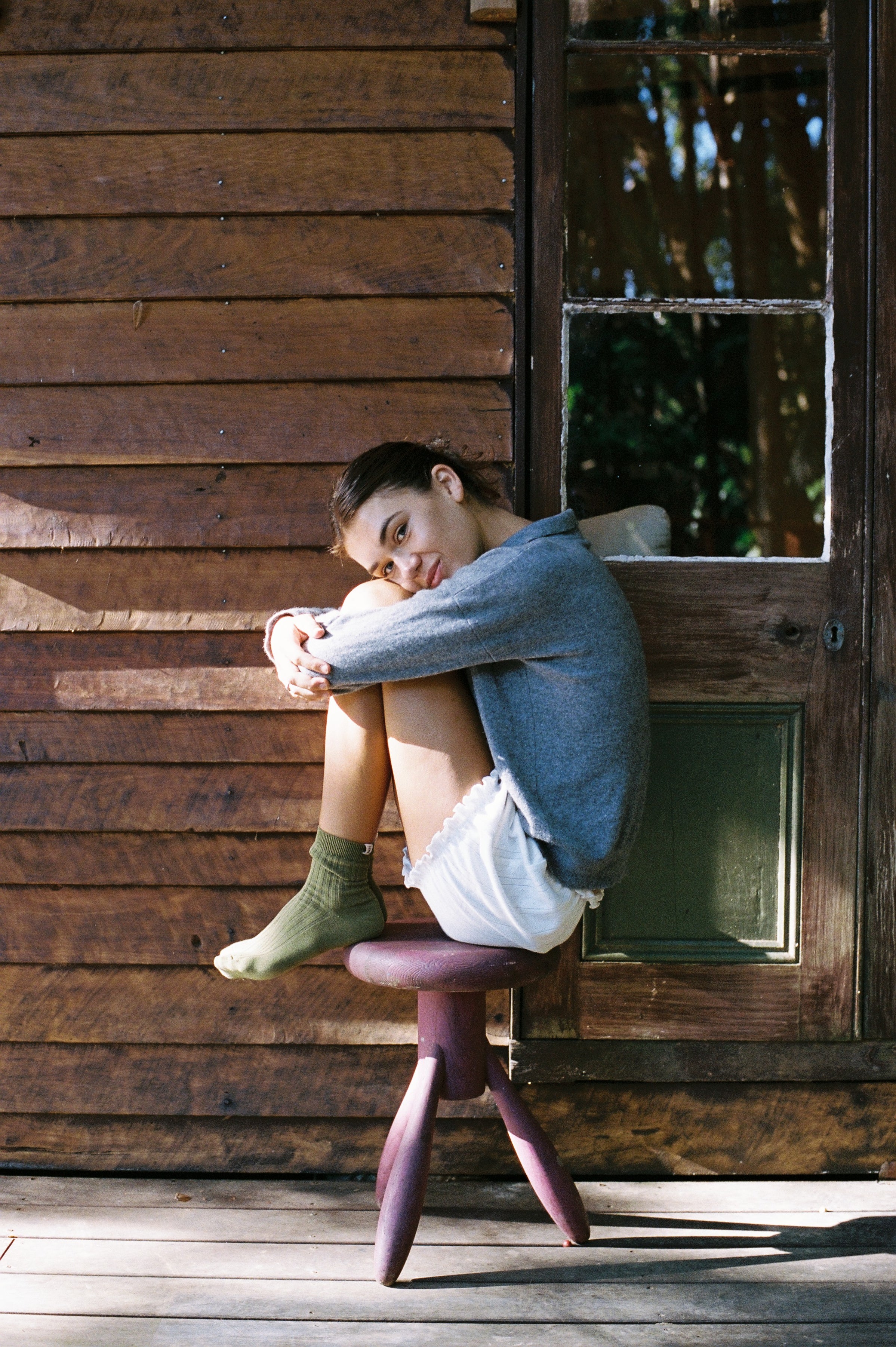 Person sitting on a wooden floor with a wooden door in the background